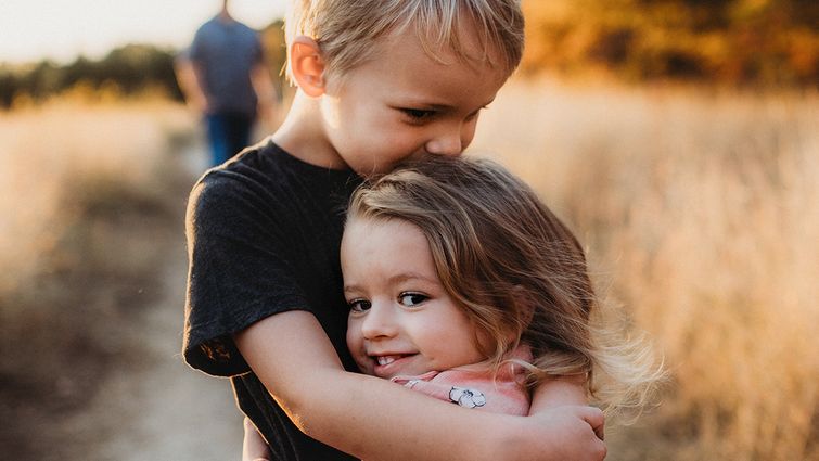two young siblings hugging