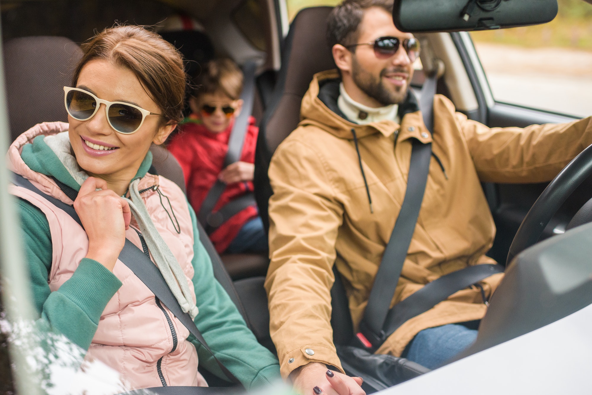 Happy friendly family travelling by car on rural road