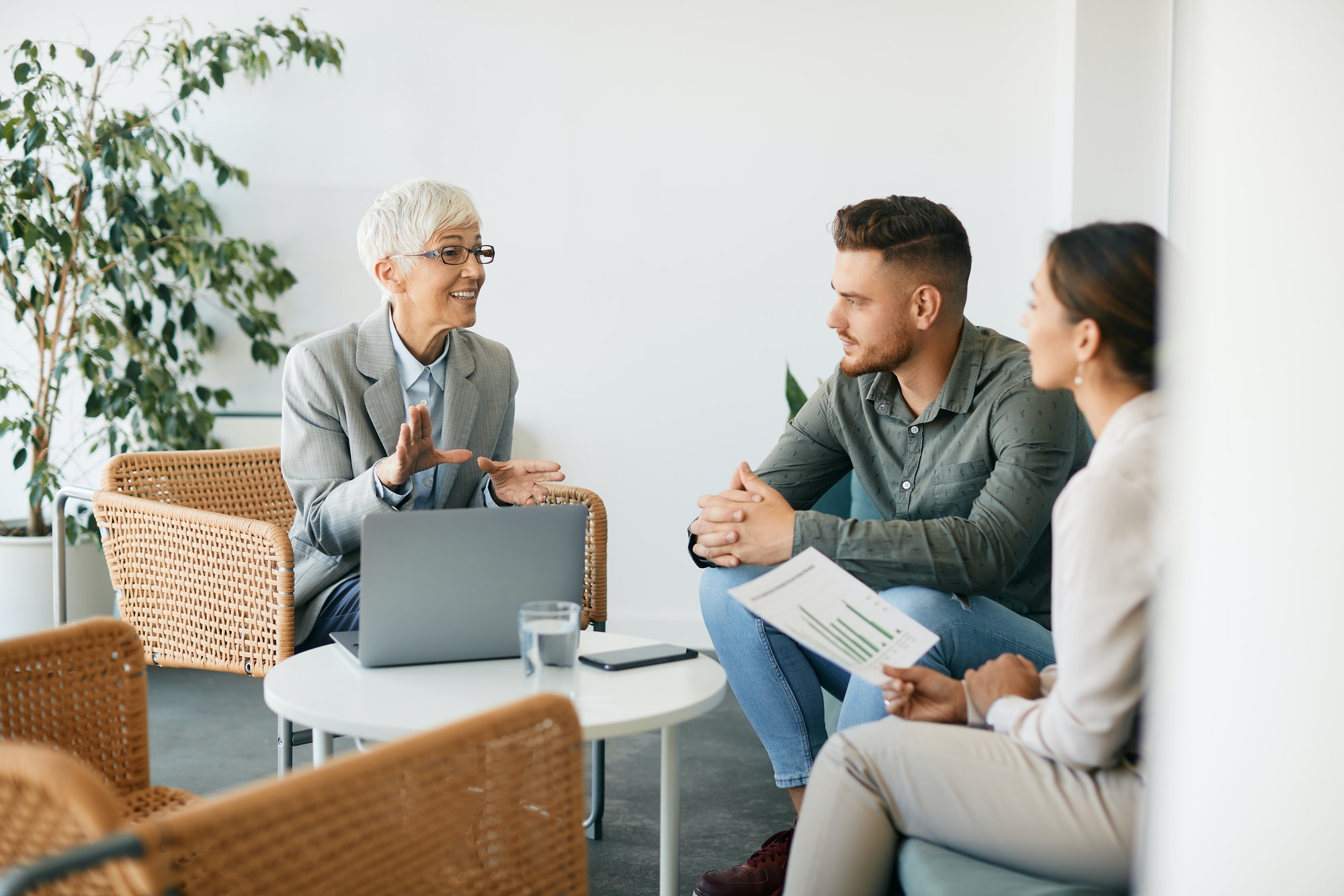 Happy senior financial adviser talking to a couple during the meeting in the office.