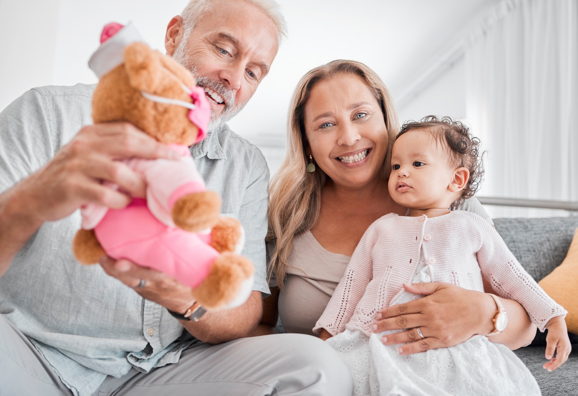 Mature, couple and baby with a toy while babysitting grand daughter with love, care and affection f