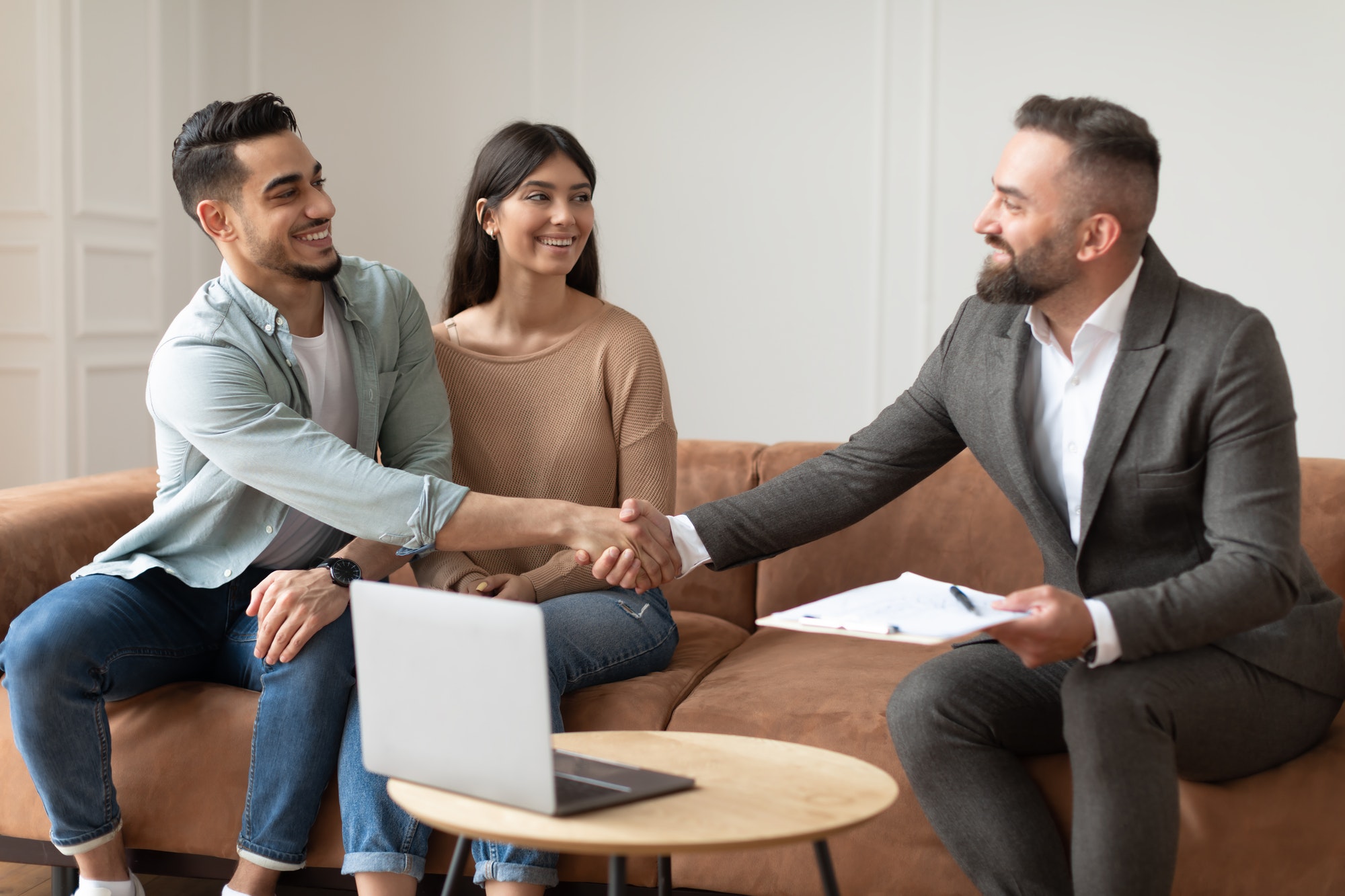 Millennial Couple Buying New Apartment, Shaking Hands With Realtor