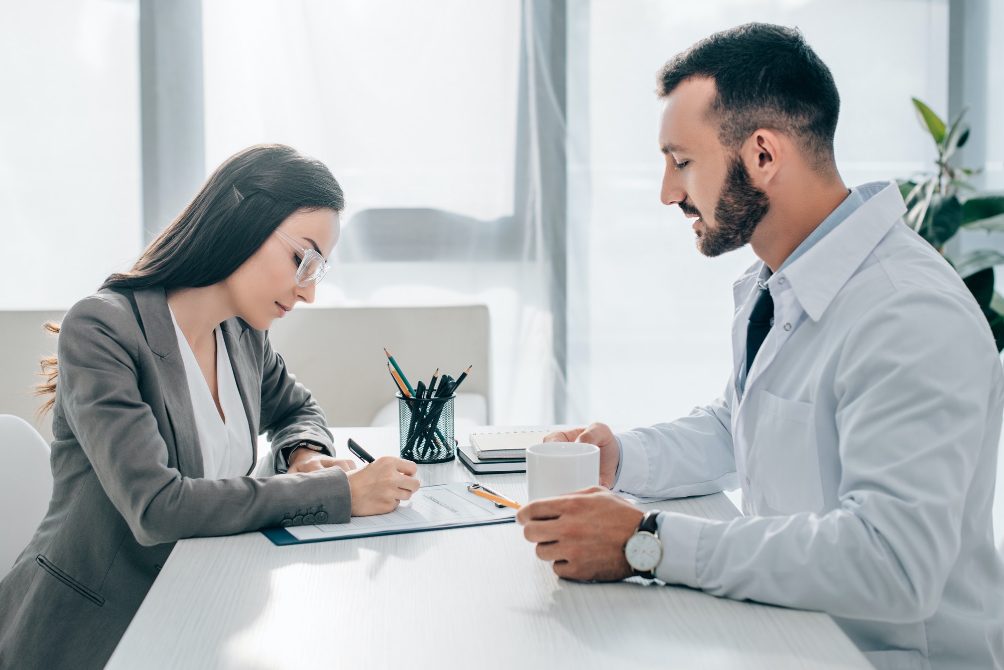 side view of patient signing insurance claim form in clinic