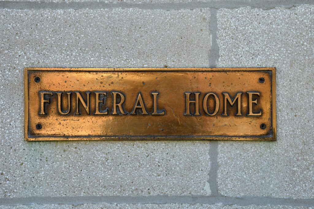 A brass Funeral Home sign on a wall. Morticians, funeral directors