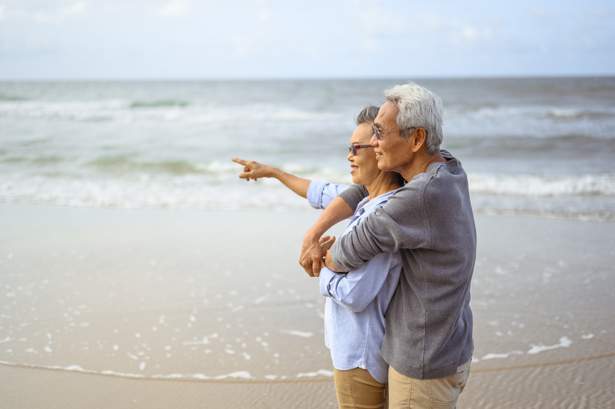 Senior couples embrace on the beach at sunny day, plan life insurance