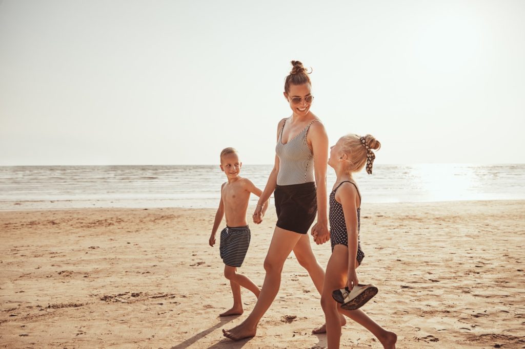 Smiling Mom and her kids walking along a sandy beach