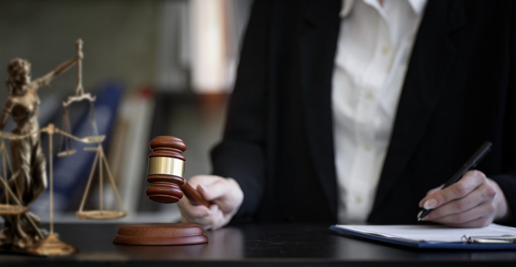 Woman judge hand holding gavel to bang on sounding block in the court room.